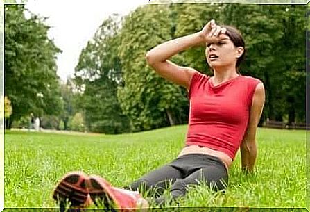 a woman sitting on the grass after exercise