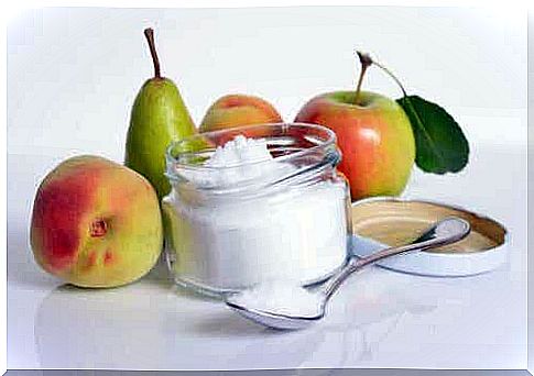 A jar of sugar surrounded by fruit.