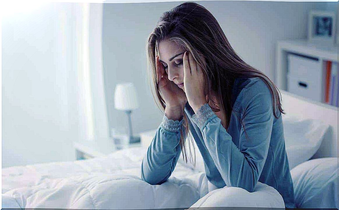 A woman sitting in bed rubbing her temples